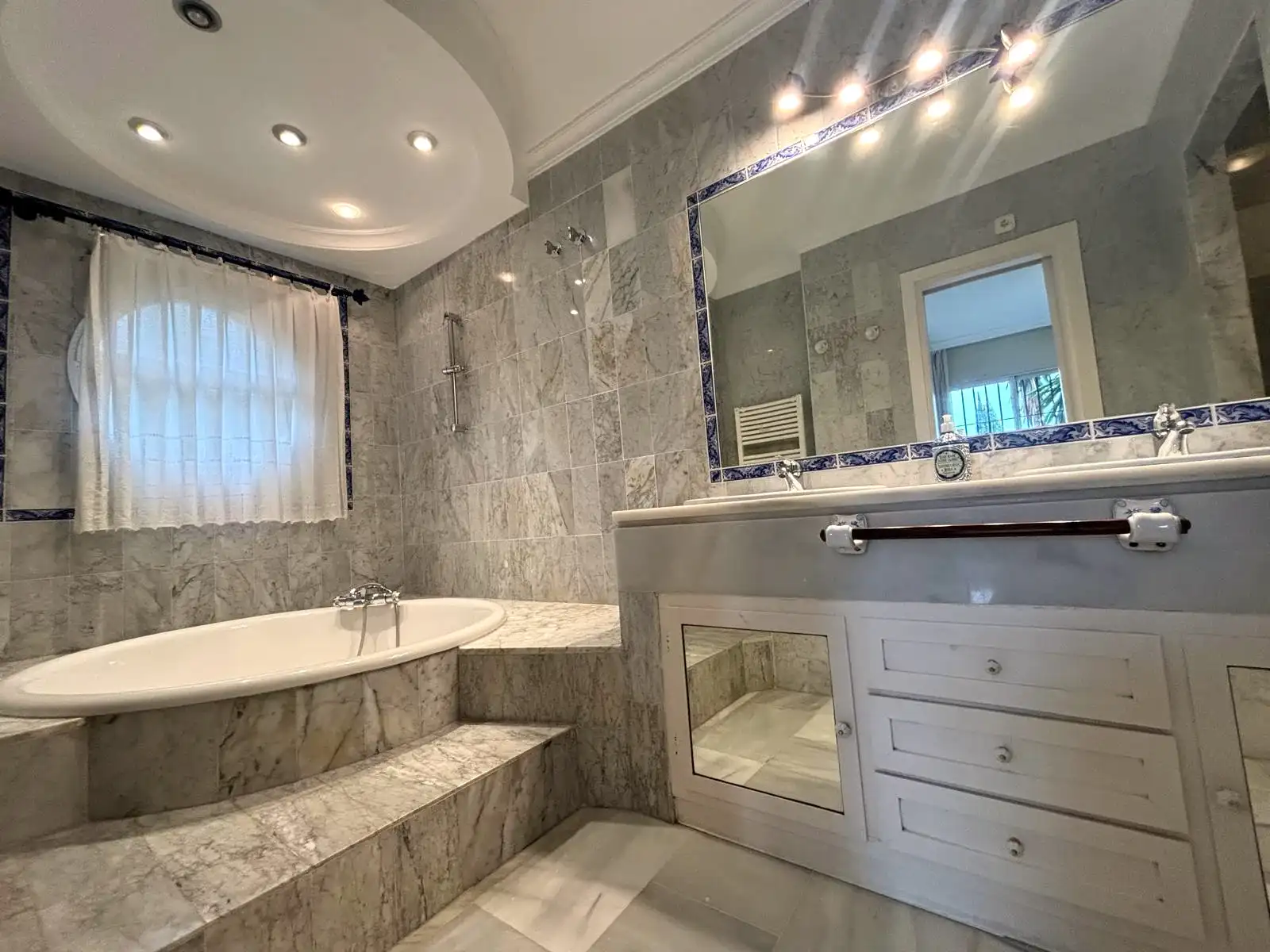 Baño principal con bañera, ventana exterior y doble lavabo en Brisas II, Manilva.