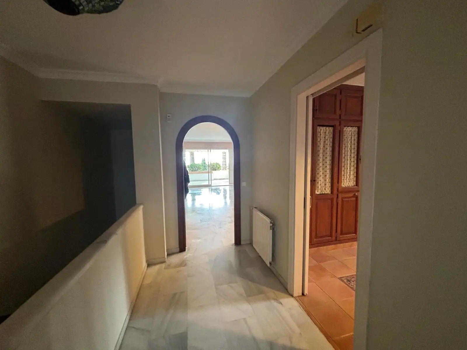 Distribuidor interior con suelos de mármol y paso hacia el salón y la zona office.