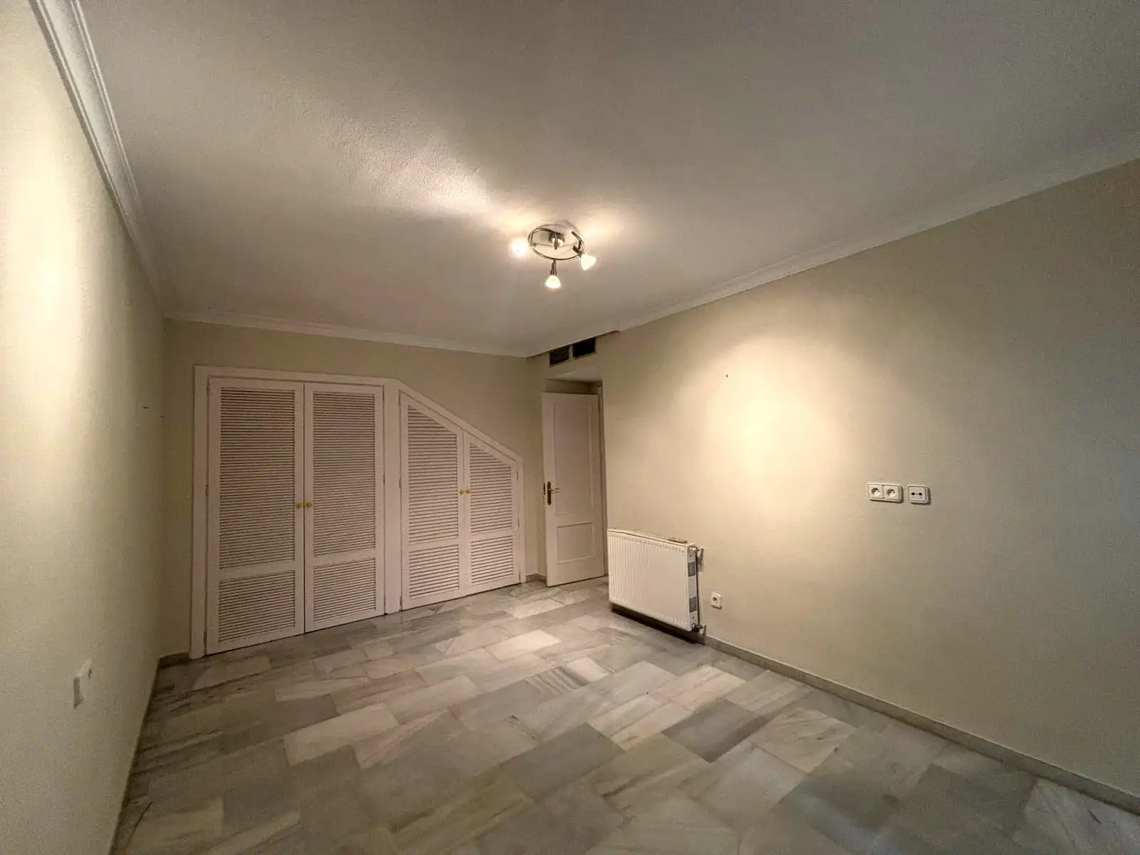 Dormitorio con armarios empotrados, radiador y suelo de mármol en Brisas II, Manilva.